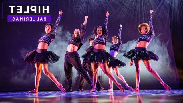 Six members of Hiplet Ballerinas of Chicago pose on stage with one arm raised in the air. They are wearing black and the stage is foggy.